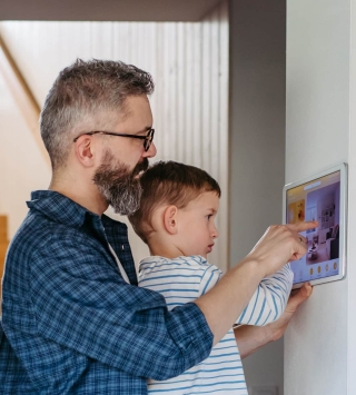 Vater und Sohn bedienen gemeinsam den Screen der Smart-Home-Technologie