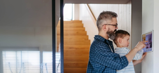 Vater und Sohn bedienen gemeinsam den Screen der Smart-Home-Technologie