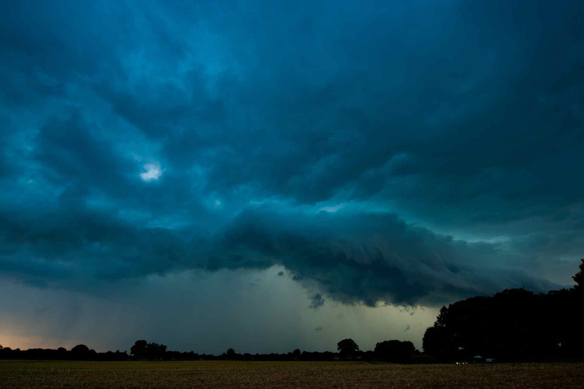 Schwarze Gewitterwolken über grüner Wiese